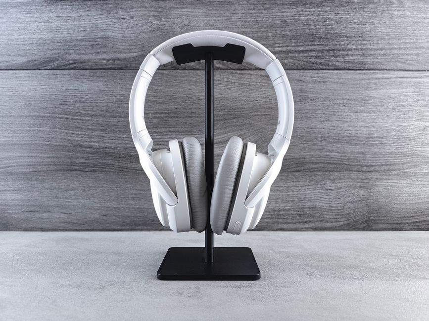 Par de fones de ouvido brancos em suporte, ideal para artigos sobre tecnologia e comunicação digital.
