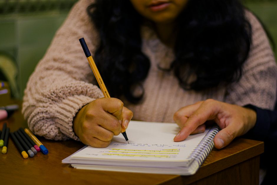 Pessoa estudando ou revisando anotações em um ambiente interno, sugerindo foco em aprendizado ou preparação de conteúdo.