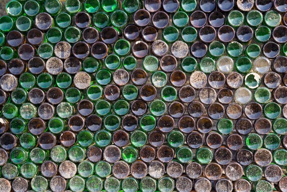 Imagem de várias garrafas de vidro empilhadas, representando sustentabilidade e reciclagem de plástico.