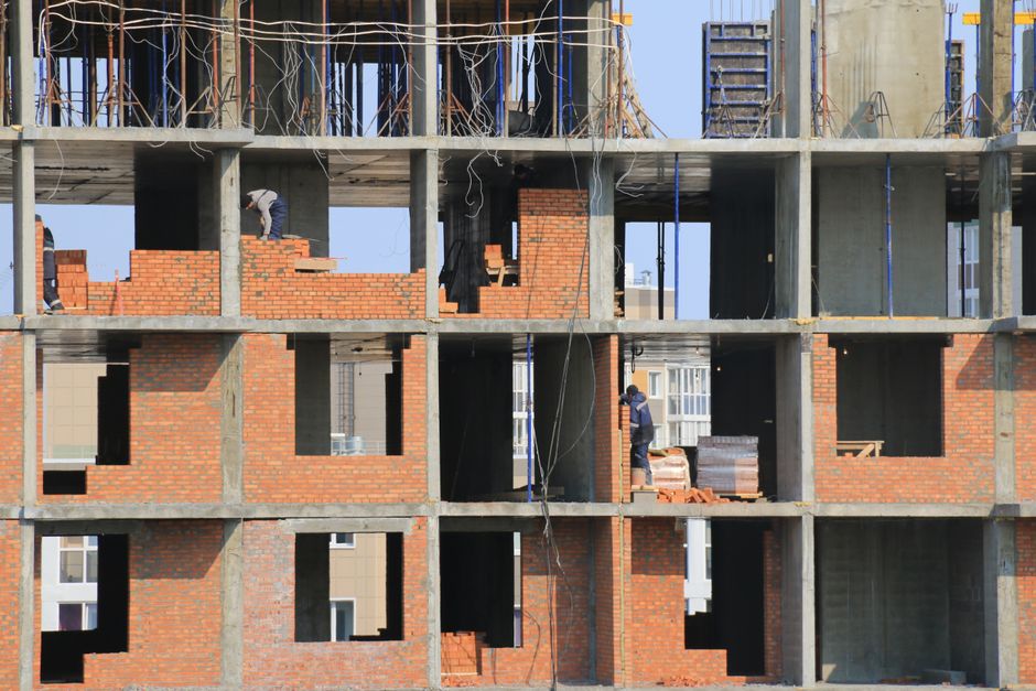 Imagem de um edifício em construção, destacando a estrutura de concreto e alvenaria em fase de montagem.