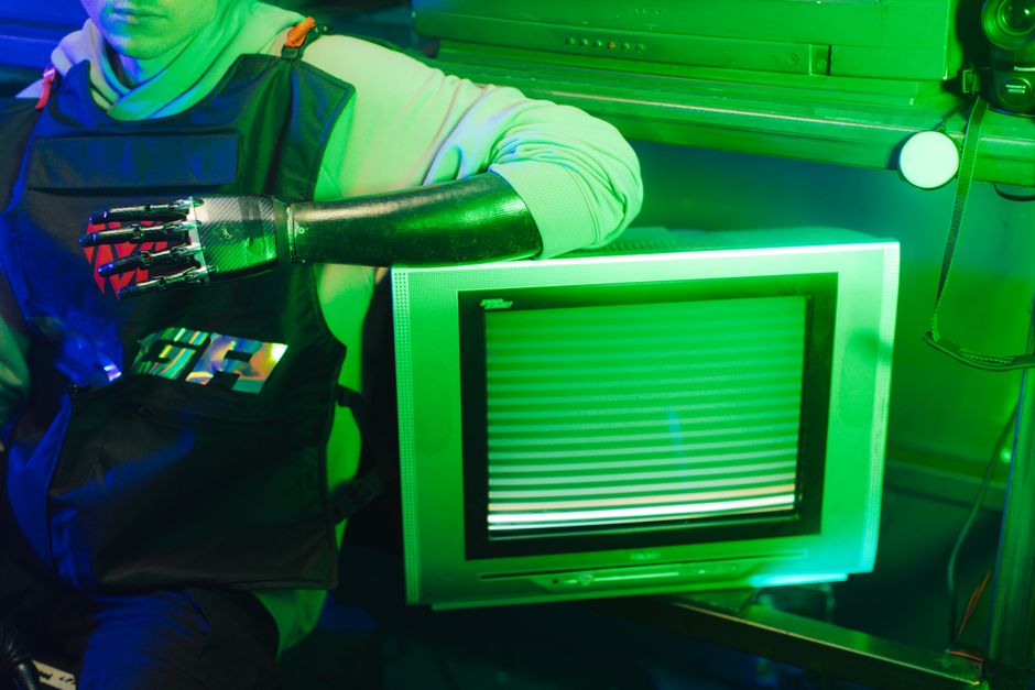 Pessoa com braço mecânico em ambiente de alta tecnologia, simbolizando inovação e robótica.