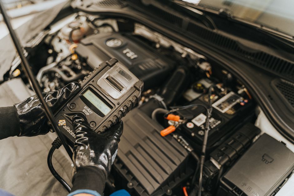 Imagem de uma pessoa realizando uma verificação no motor de um carro, simbolizando manutenção ou diagnóstico automotivo.