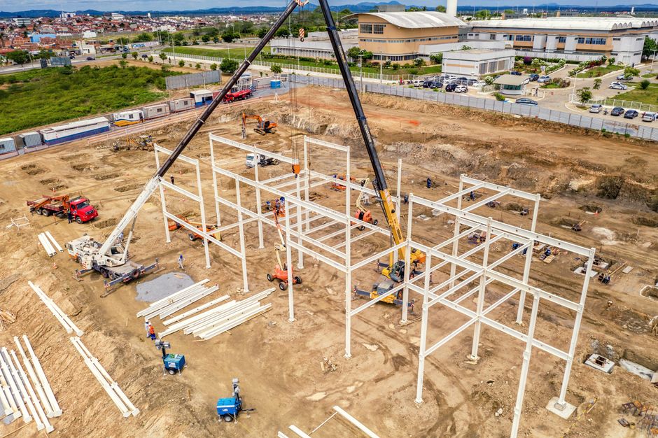 Construção de uma estrutura metálica em um canteiro de obras, representando desenvolvimento de novas instalações comerciais ou industriais.