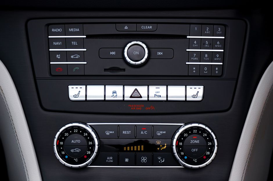 Painel de controle de ar-condicionado e sistema de entretenimento em um carro, destacando tecnologia e conforto automotivo.