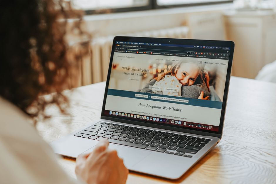 Pessoa navegando em um site de adoção de crianças em um ambiente doméstico, ilustrando interesses sociais e de responsabilidade.