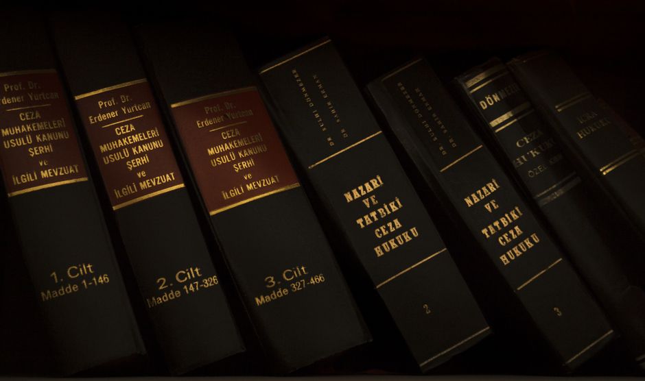 Imagem de livros jurídicos relacionados ao direito penal e processo penal dispostos em uma estante, enfatizando o tema do estudo ou pesquisa na área jurídica.