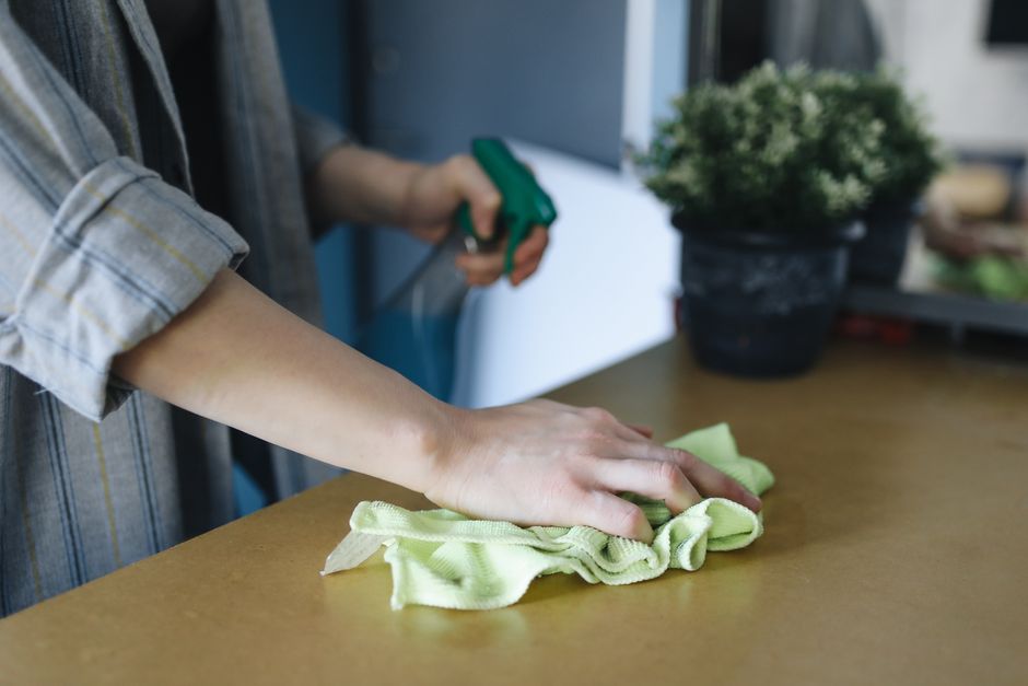 Pessoa limpando uma mesa com um pano de limpeza ao ar livre, destacando cuidados com ambientes externos e manutenção doméstica.