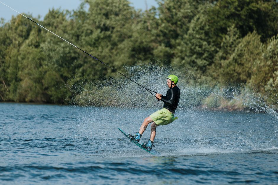 Pessoa praticando wakeboard em um ambiente ao ar livre, destacando a atividade de esportes aquáticos e lazer.