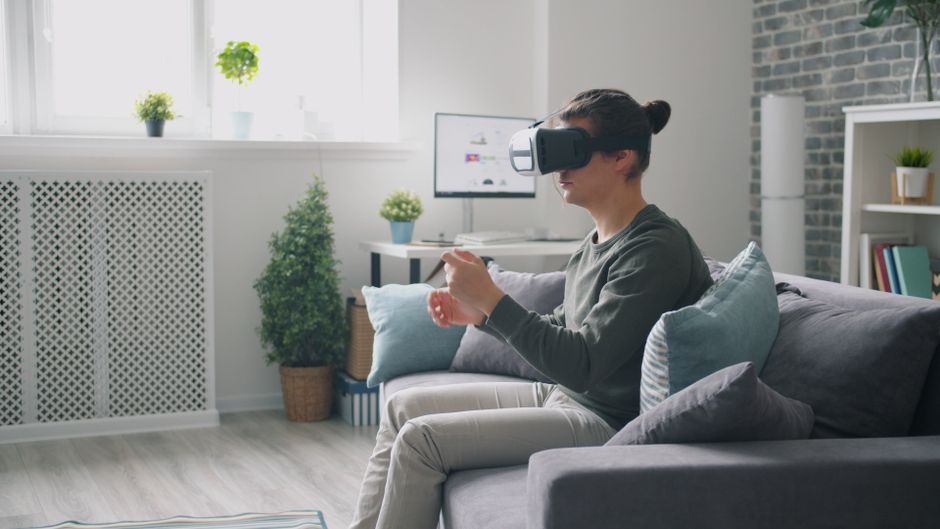 Pessoa interagindo com realidade virtual em um ambiente doméstico, explorando tecnologia e inovação.