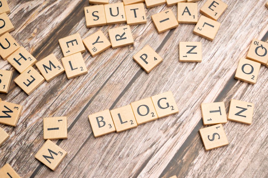 Imagem com peças de scrabble formando palavras relacionadas a gestão de conteúdo e blogs digital, sobre uma superfície de madeira rusticada.