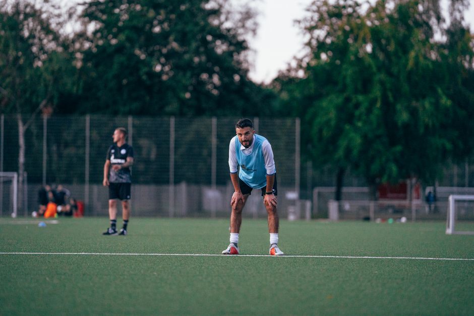Jogador de futebol em treino ou partida, focado na preparação física e técnica em um campo ao ar livre.