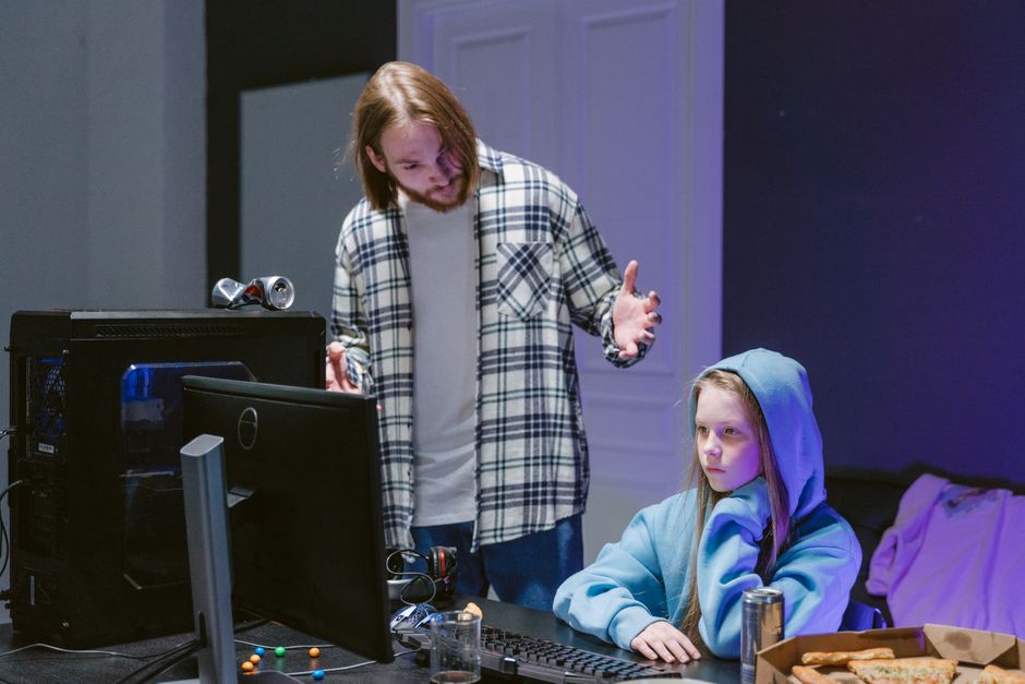 Jovem e menina concentrados em uma atividade de jogos ou criação digital, em um ambiente interno confortável e moderno.