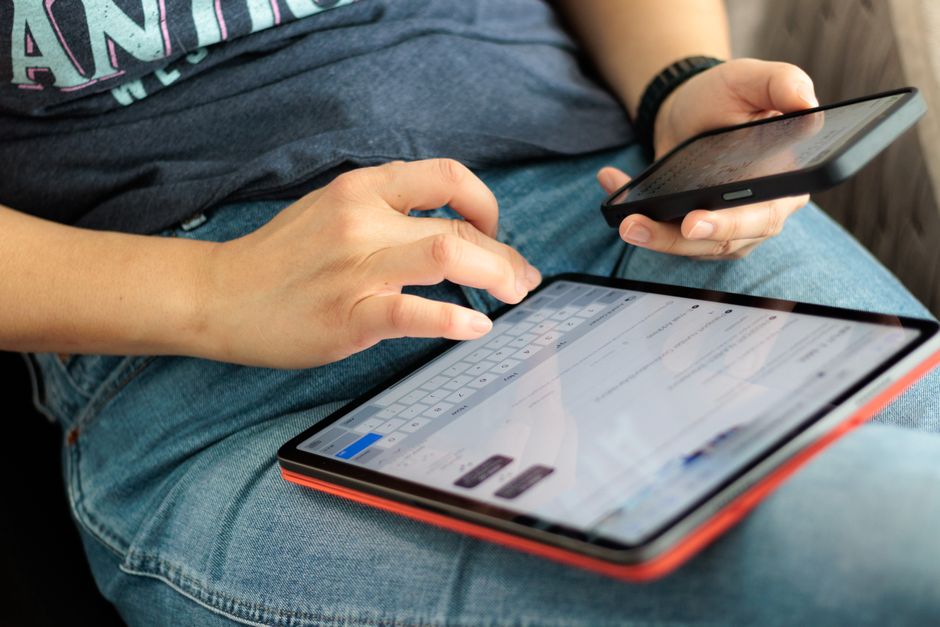 Pessoa utilizando dispositivos móveis para gerenciar suas finanças pessoais ou profissionais de forma digital.