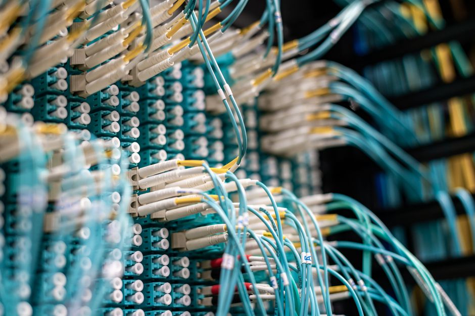 Imagem de um centro de cabeamento estruturado com cabos e conectores usados em infraestrutura de redes de computadores.