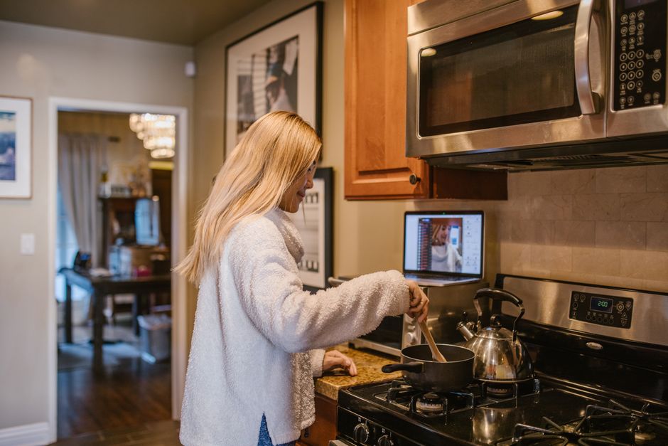Mulher cozinhando na cozinha com foco na preparação de uma refeição caseira, destacando o ambiente doméstico.