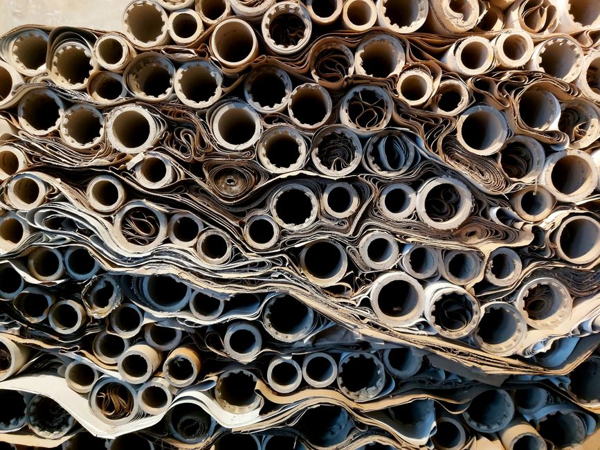 Pilhas de papel de jornais e documentos enrolados organizados em um monte, prontos para descarte ou reciclagem, refletindo temas de sustentabilidade ou gestão de resíduos.