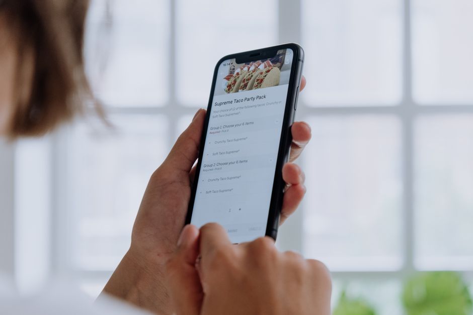 Pessoa usando um smartphone para fazer um pedido de comida online, simbolizando conveniência na rotina diária.