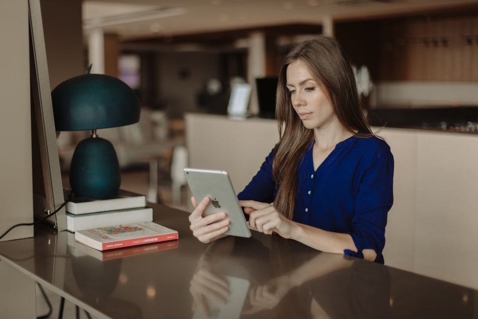 Mulher trabalhando em um ambiente de escritório usando um tablet, simbolizando produtividade e trabalho remoto.