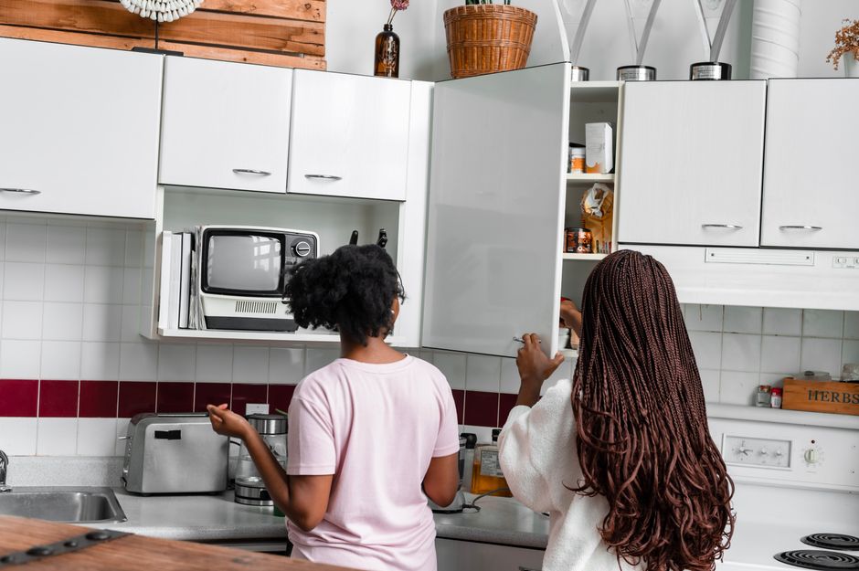 duas pessoas jovens organizando a cozinha de forma colaborativa, refletindo convivência e rotina doméstica