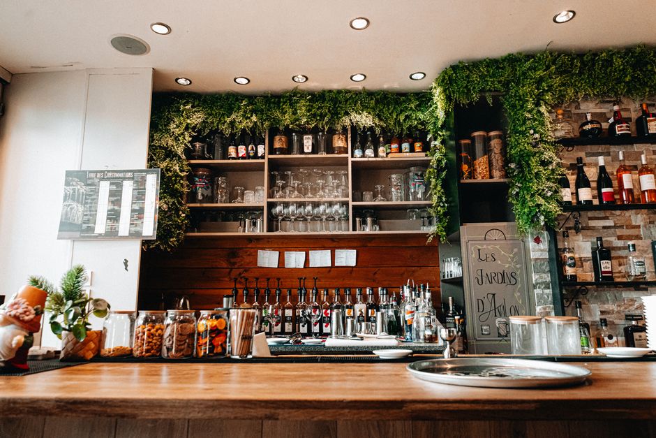 Imagem de um bar com decoração aconchegante e arbustos verdes, ideal para artigos sobre hospitalidade, bares e negócios no setor de alimentação