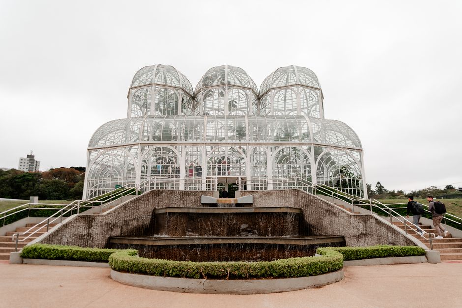 Estrutura de uma estufa de vidro formando um prédio futurista em um parque ao ar livre.