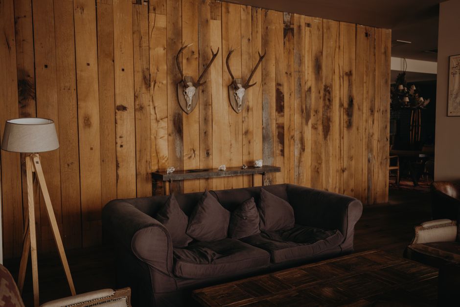 Ambiente aconchegante com decoração rústica, incluindo painel de madeira e objetos de caça na parede, ideal para um blog sobre decoração de interiores com estilo boho ou fazenda.