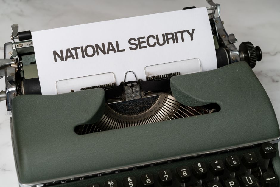 Máquina de escrever antiga exibindo um documento com o título 'NATIONAL SECURITY', simbolizando questões relacionadas à segurança nacional e inteligência.