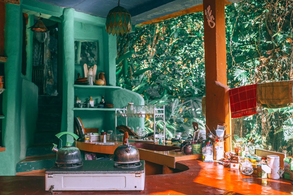 Cozinha rústica integrada à natureza, com elementos de uso cotidiano e decoração artesanal, transmitindo aconchego e conexão com o ambiente externo.