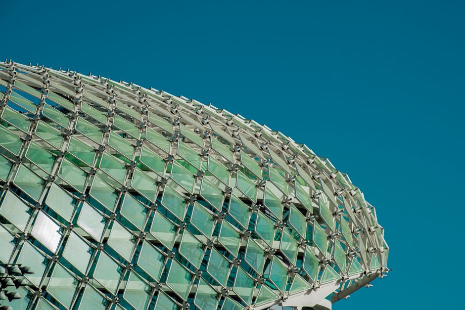 Imagem de um edifício contemporâneo com fachada de vidro, destacando seu design moderno e arquitetônico.