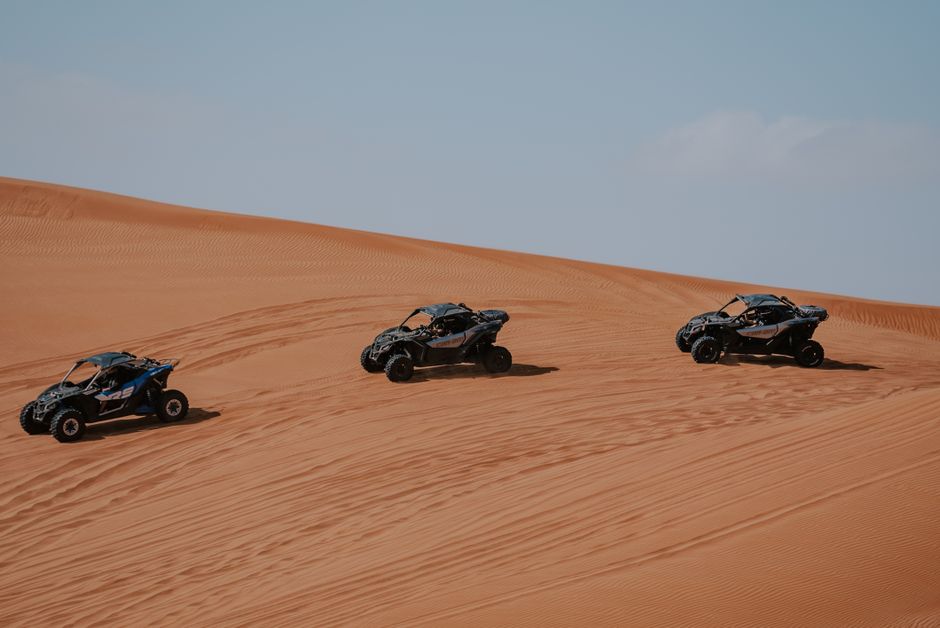 Veículos off-road desbravando dunas de areia em um cenário de deserto, destacando aventura e superação de obstáculos.