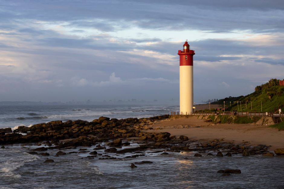 Farol à beira-mar ao entardecer, simbolizando orientação e segurança na zona costeira.
