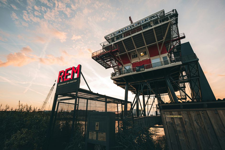 Estrutura de um edifício de observação ou controle em uma área industrial, destacando uma instalação elevada ao pôr do sol.