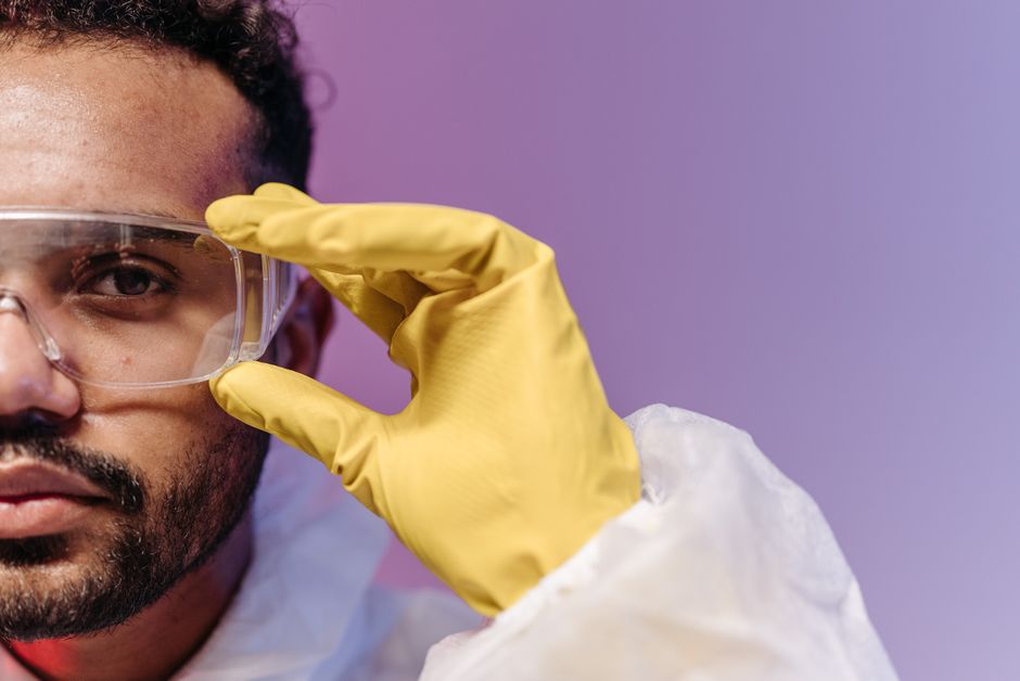 Jovem cientista ajustando seus óculos de proteção em um laboratório, simbolizando pesquisa e experimentação científica.