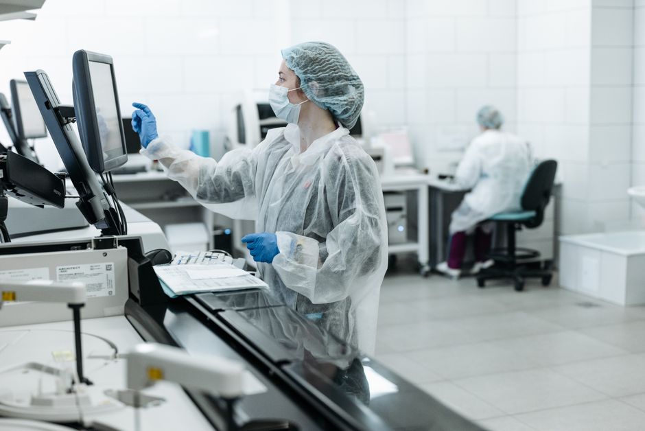 Profissional de saúde em laboratório realizando análise ou pesquisa em ambiente hospitalar ou de pesquisa científica.