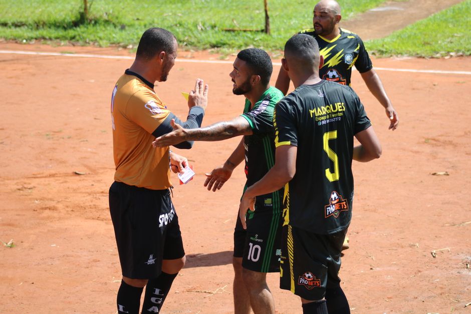Jogadores de futebol em campo durante partida, comemorando ou conversando no gramado ao ar livre.