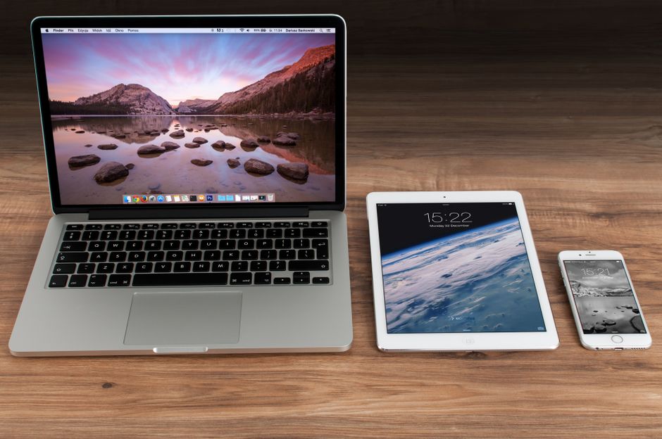 Imagem de dispositivos eletrônicos, incluindo um laptop, um tablet e um smartphone, dispostos sobre uma superfície de madeira, indicada para artigos sobre tecnologia ou produtividade digital.