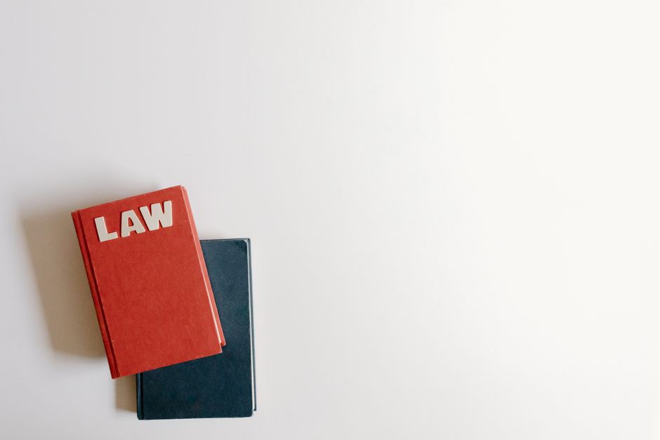 Duas livros, sendo um com capa vermelha e a palavra 'LAW' em destaque, sobre uma mesa branca, simbolizando direito e legislação.