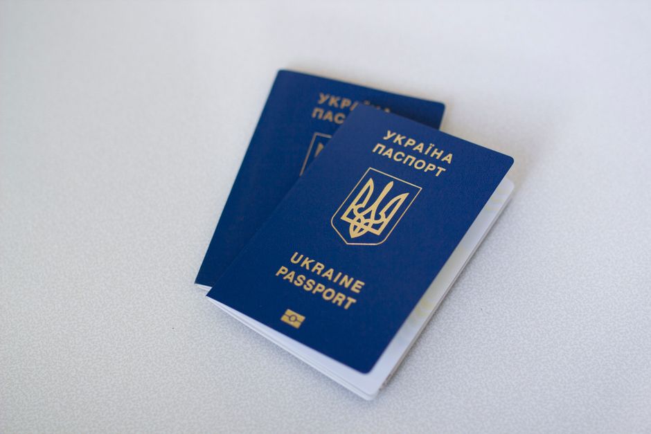 Imagem de dois passaportes ucranianos sobre uma superfície clara, simbolizando viagem internacional ou documentos de identidade.
