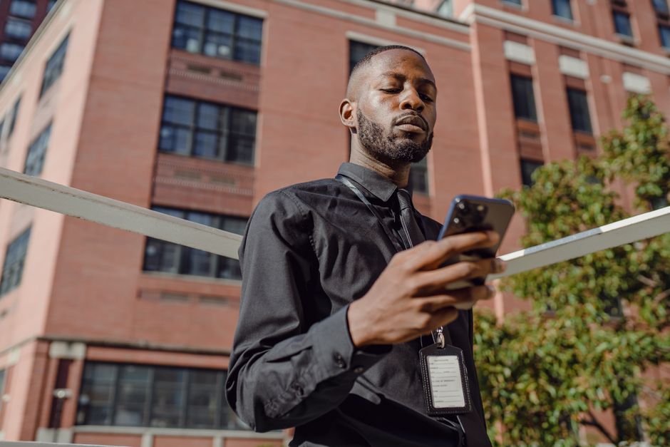 Homem usando smartphone em ambiente urbano, representando a conexão digital no contexto de negócios e comunicação moderna.