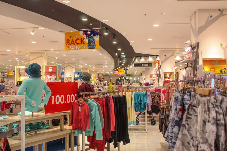 Imagem de uma loja de roupas no shopping, destacando a área de vestuário infantil e a movimentação de clientes durante o retorno às aulas.