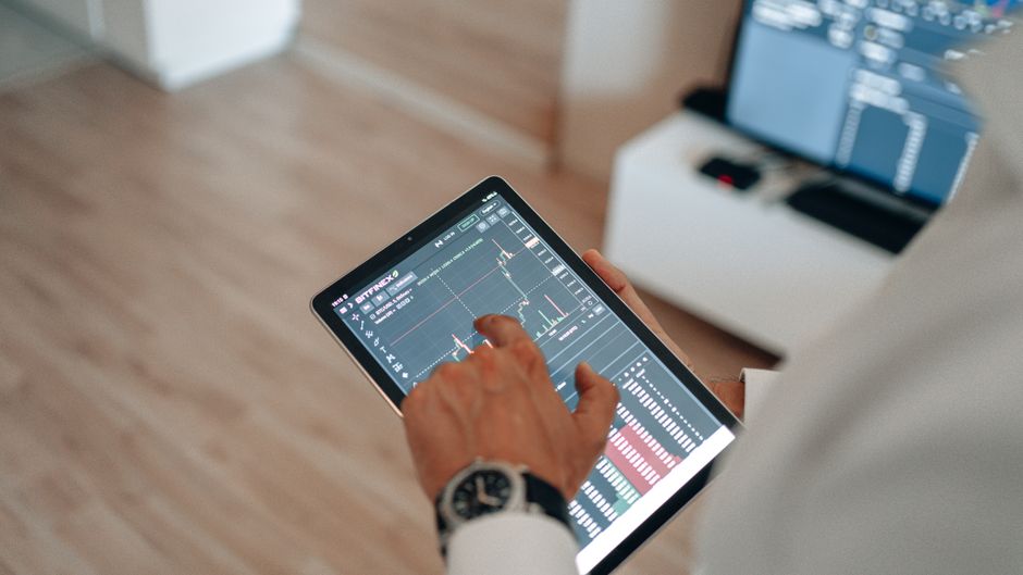 Pessoa analisando gráficos de investimentos em um tablet, simbolizando gestão financeira e estratégias de mercado.