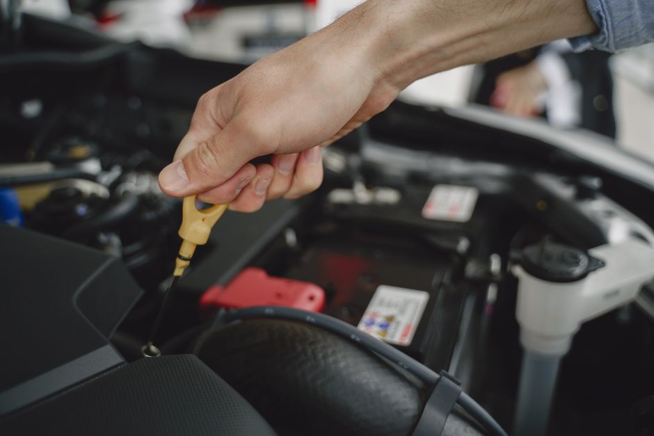 Pessoa realizando manutenção ou inspeção em um motor de carro, simbolizando cuidado técnico e mecânico.