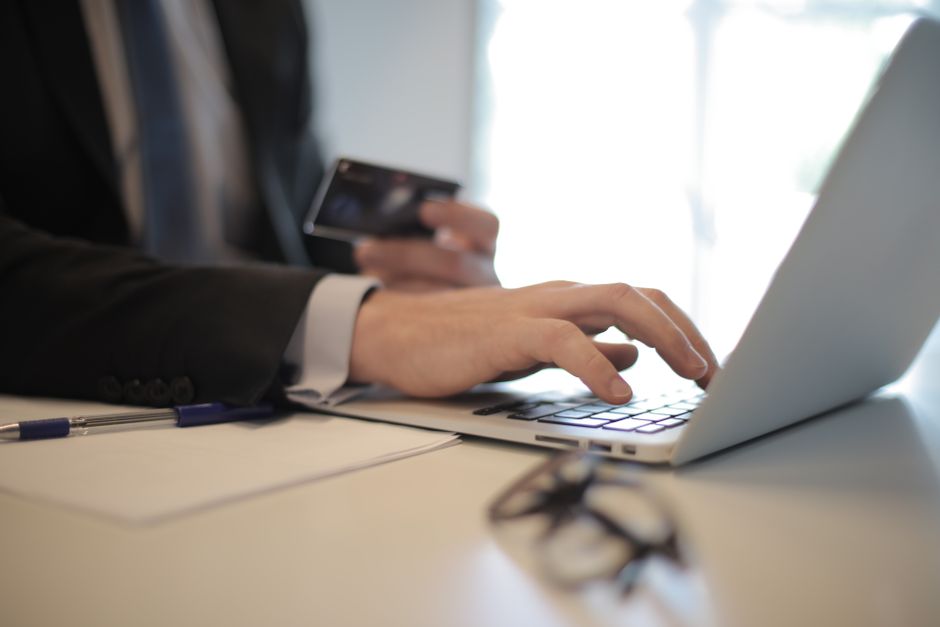 Homem de negócios trabalhando em um laptop com smartphone em um ambiente de escritório, representando produtividade e tarefas digitais.