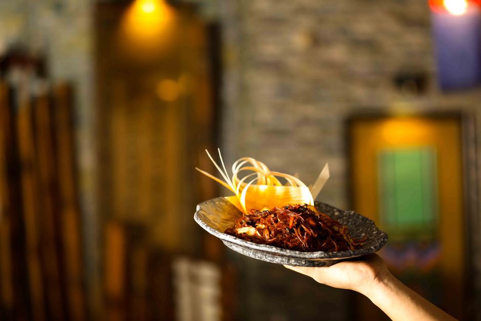 Pessoas próximas ao fogão no restaurante da/fábrica que apresenta pratos gourmet ou tradicionais, destacando o ambiente de gastronomia com uma seleção de comida artesanal ou de alta qualidade.