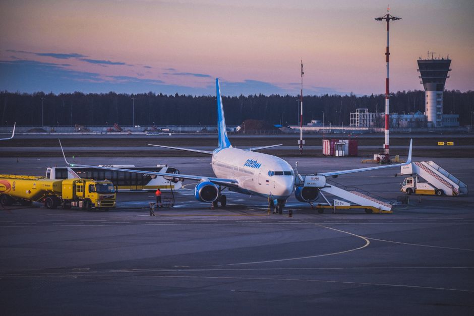 Imagem de um avião decolando ou taxiando no aeroporto durante o pôr do sol, destacando o setor de aviação e viagens.