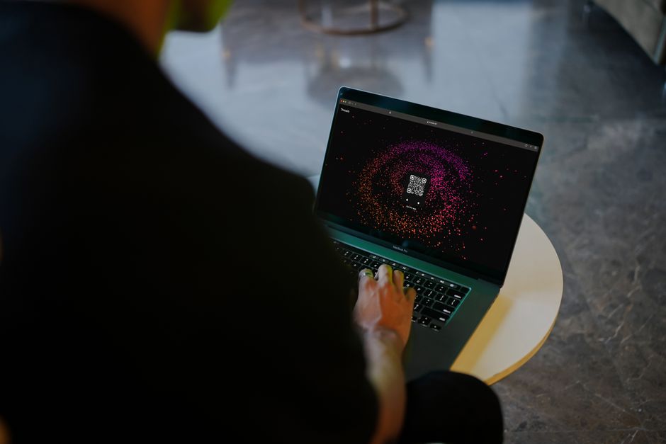 Pessoa usando um laptop com código QR na tela, representando tecnologia e segurança digital.