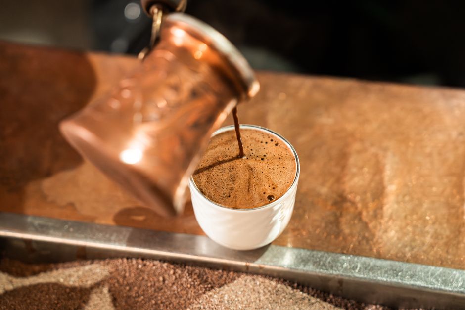 Foto de um café expresso sendo preparado em uma cafeteria aconchegante, enfatizando a experiência de consumo de café.
