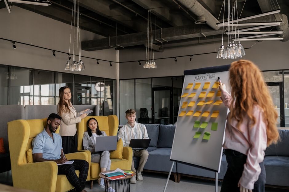 Equipe de profissionais participando de uma reunião estratégica em um ambiente de coworking, com apresentação de planejamento de marketing.