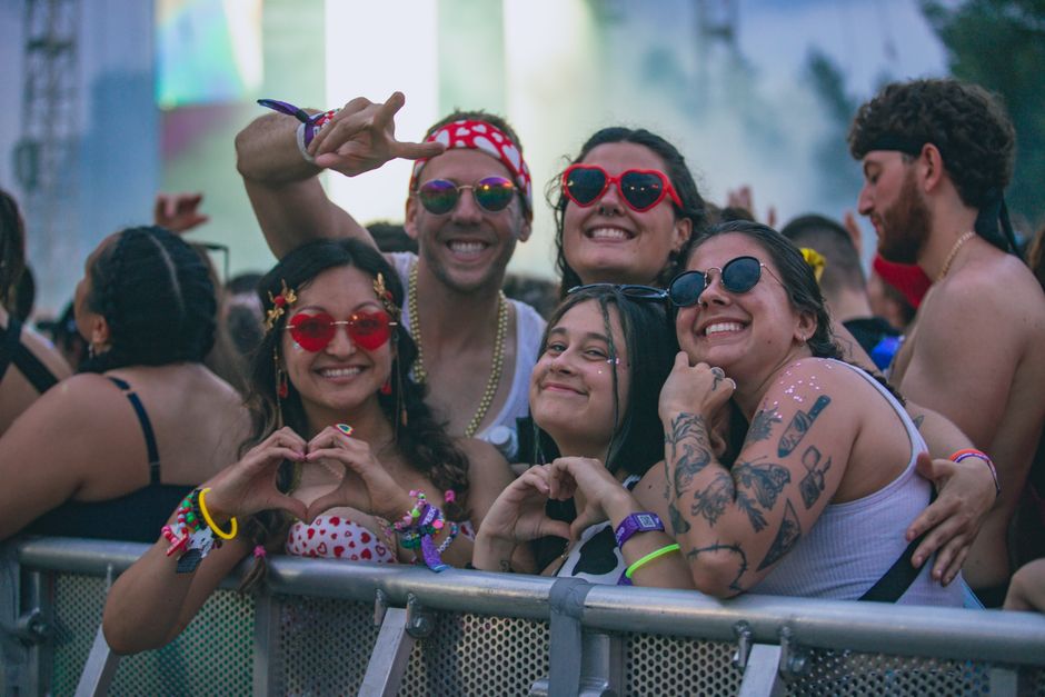 Grupo de amigos curtindo um festival ao ar livre, demonstrando alegria e descontração em ambiente de música e celebração.