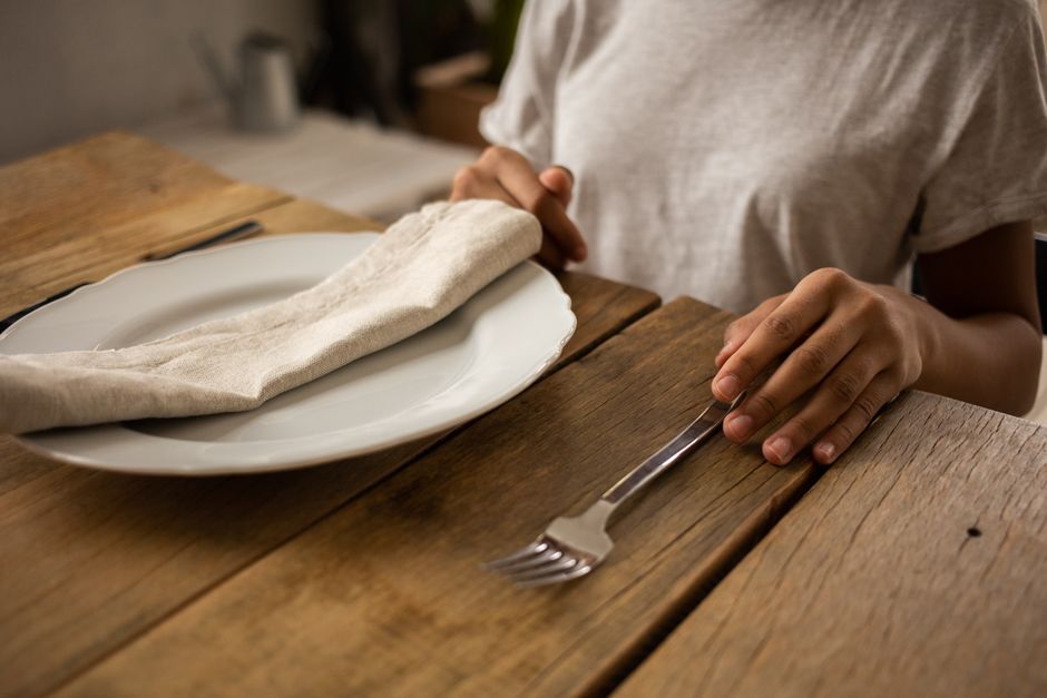 Pessoa arrumando a mesa de forma elegante e minimalista para uma refeição ou evento social, com foco na organização e apresentação.
